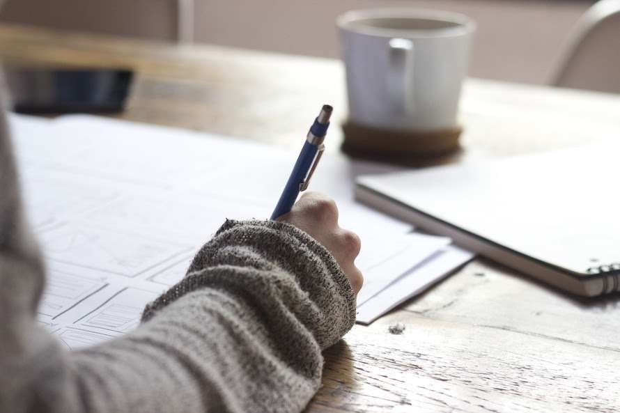 Hand Depicted Writing with Pen on Desk