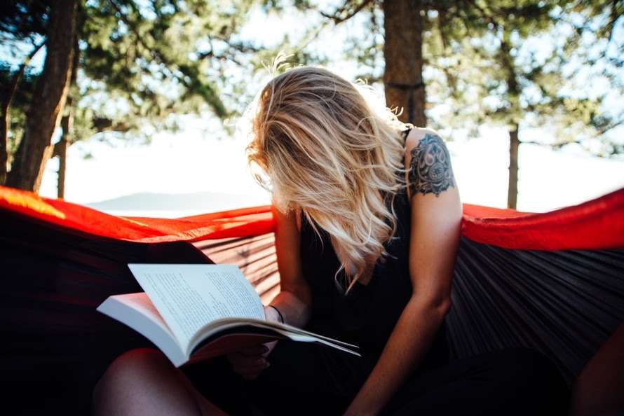 Woman Reading Book on Bench in Park